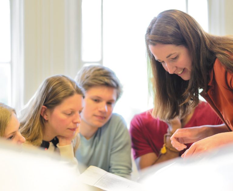 A lecturer and students looking at a book