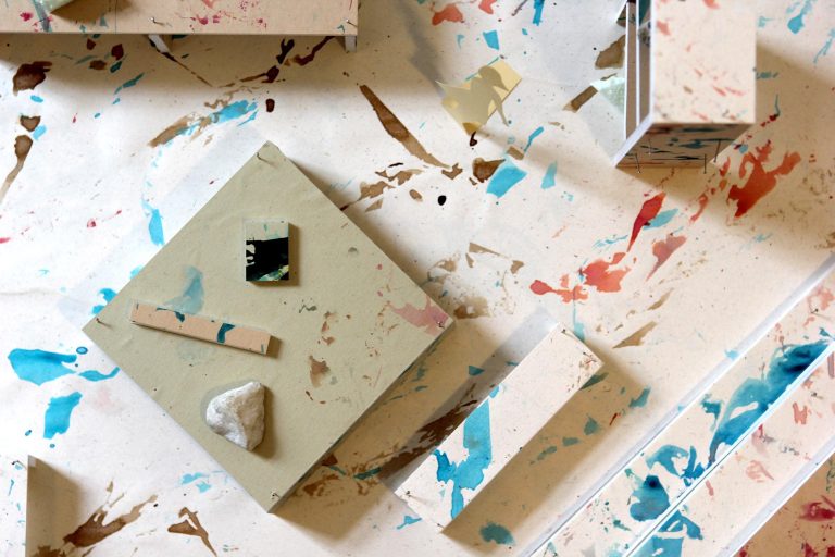 View of a floor from above with flecks of paint and rectangular and square blocks of different heights and widths.