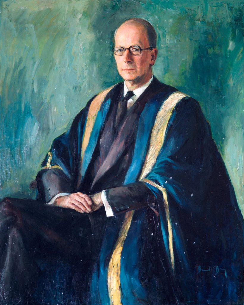 Portrait of a seated John Frederick Wolfenden. A bespectacled Wolfenden is wearing academic robes with a blue and gold trim, over a navy suit.