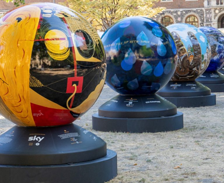 Four globes, each painted in a different style, on black plinths.
