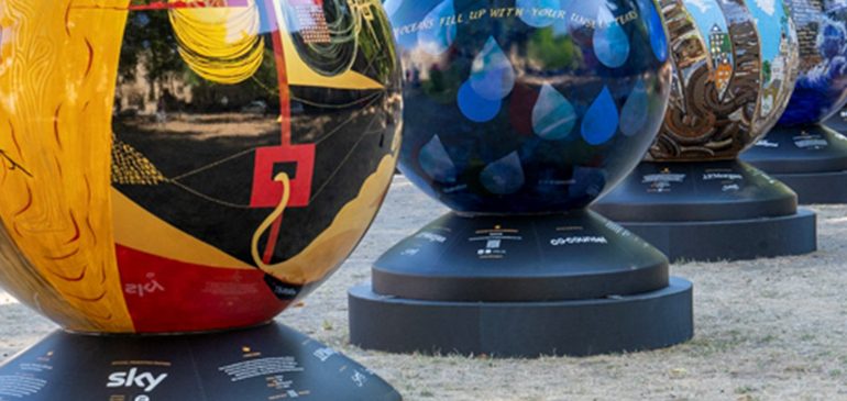 Four globes, each painted in a different style, on black plinths.