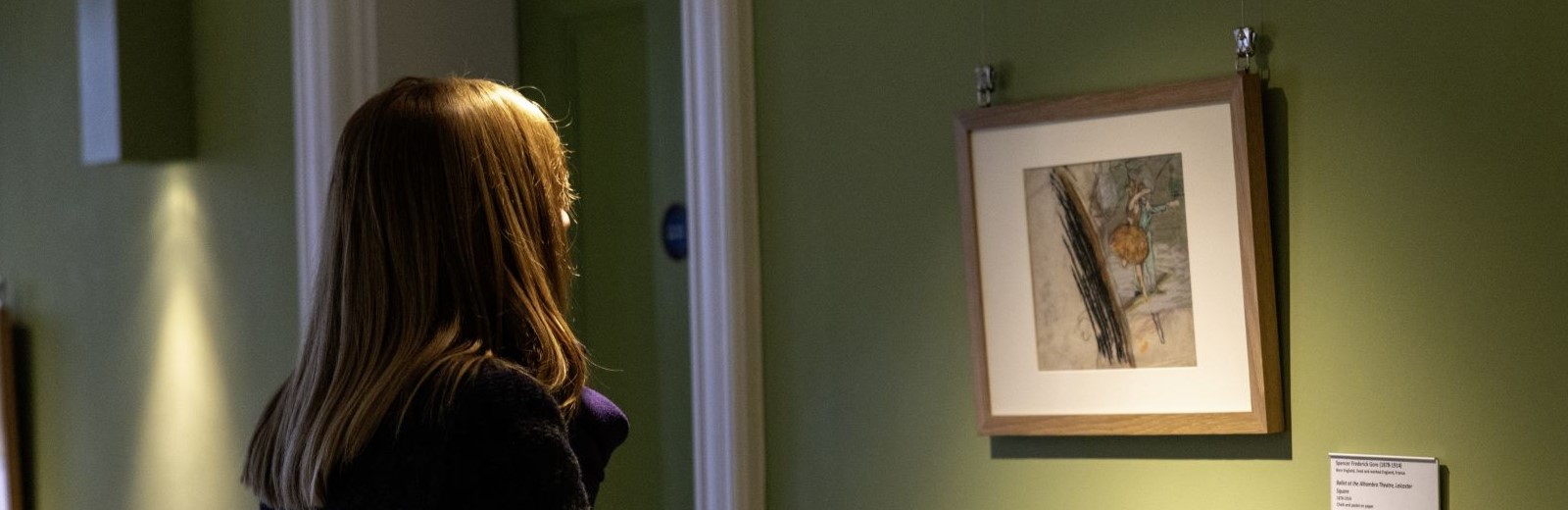 Woman looking at an artwork of two figures dancing.