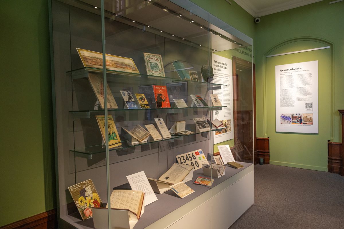 A large glass display case containing various archives and library items on shelves