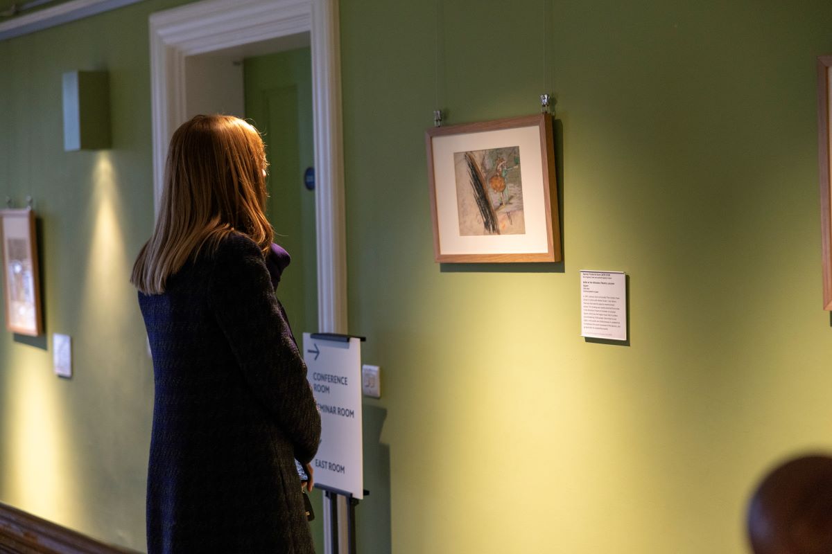 A visitor looking at a painting in the staircase hall