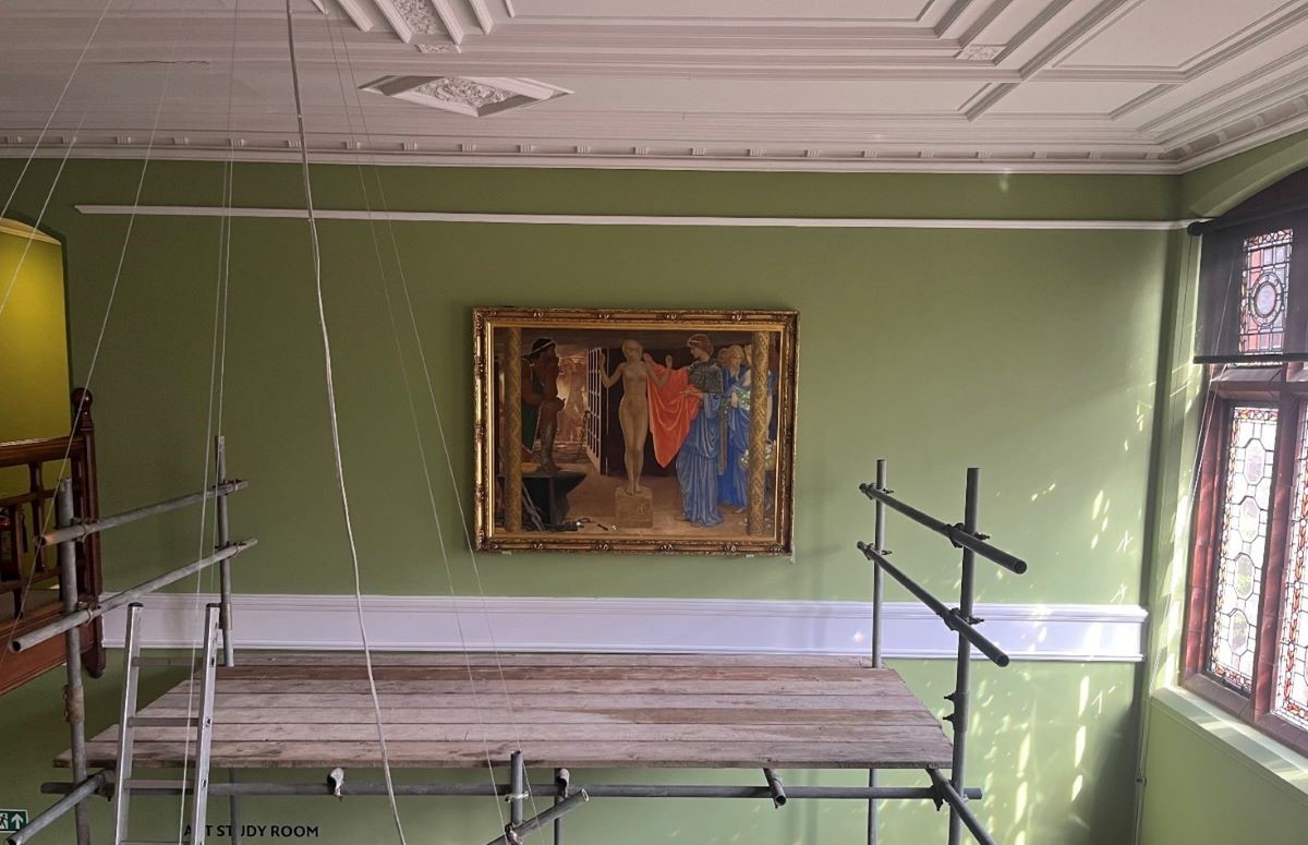 Painting of Pandora on a large green wall next to a window with scaffolding below