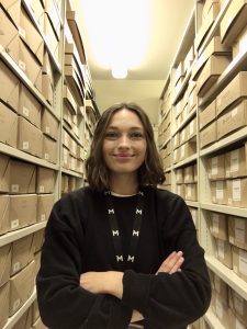 Rebecca Keddie, graduate trainee archive assistant, standing in the archive store.