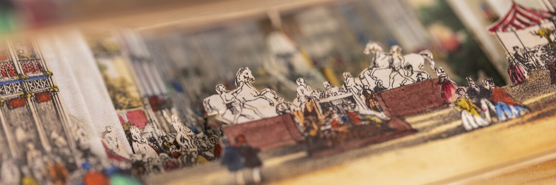 Coloured paper scene showing figures, horses, and architectural details inside the Crystal Palace at the Great Exhibition of 1851, taken from Lane’s telescopic view.