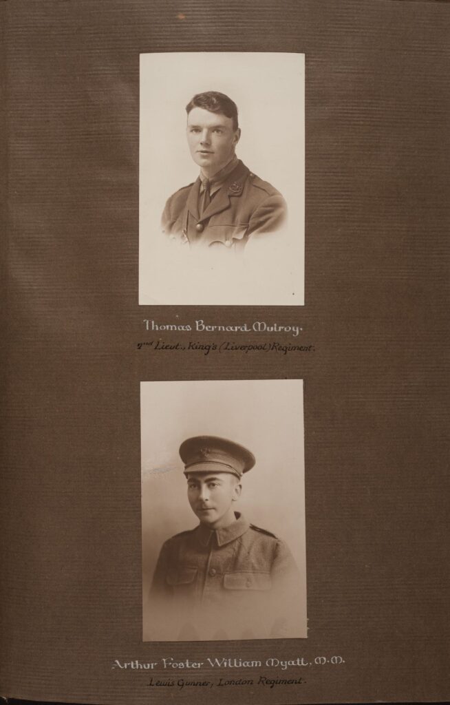Mounted page showing two sepia portrait photographs of individuals wearing military uniforms, arranged one above the other on a brown backing board. Beneath each photograph is printed identification text. The upper portrait is captioned “Thomas Bernard Mulroy, 2nd Lieutenant, King’s (Liverpool) Regiment.” The lower portrait is captioned “Arthur Foster William Myatt, M.M., Lewis Gunner, London Regiment.” The photographs are formal studio portraits with plain backgrounds.