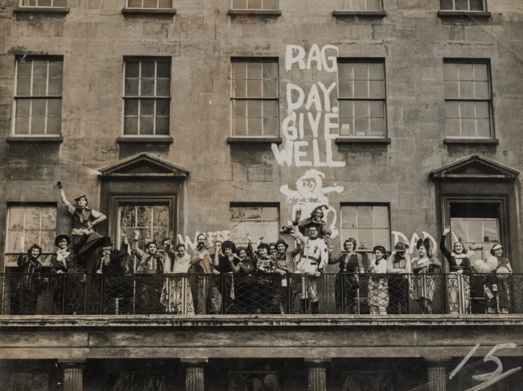 Students in fancy dress standing on a balcony