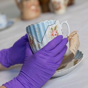 Close up of staff wearing purple gloves looking at ceramics in the mezzanine learning space in the open store.